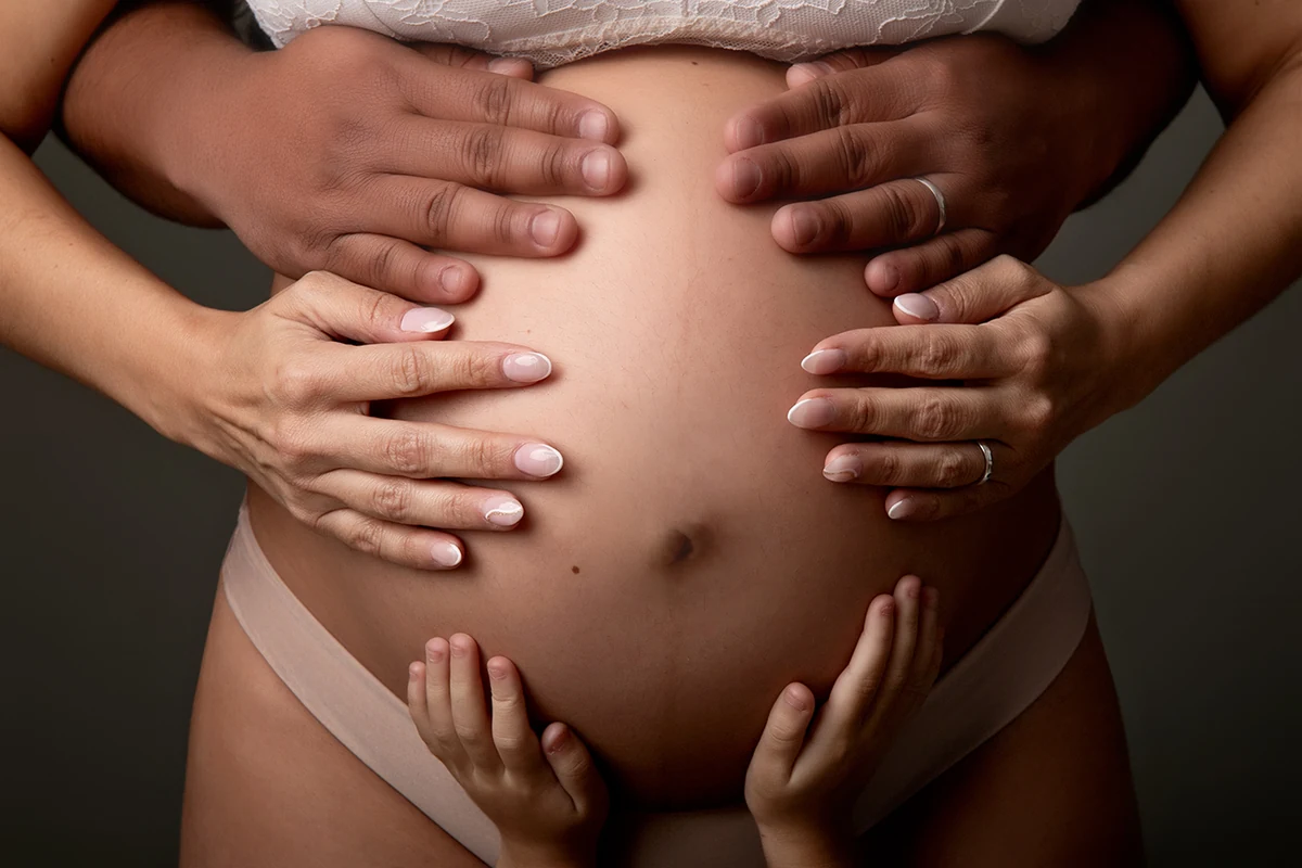 Manos de la familia sobre la barriga en una sesión de embarazo en El Masnou