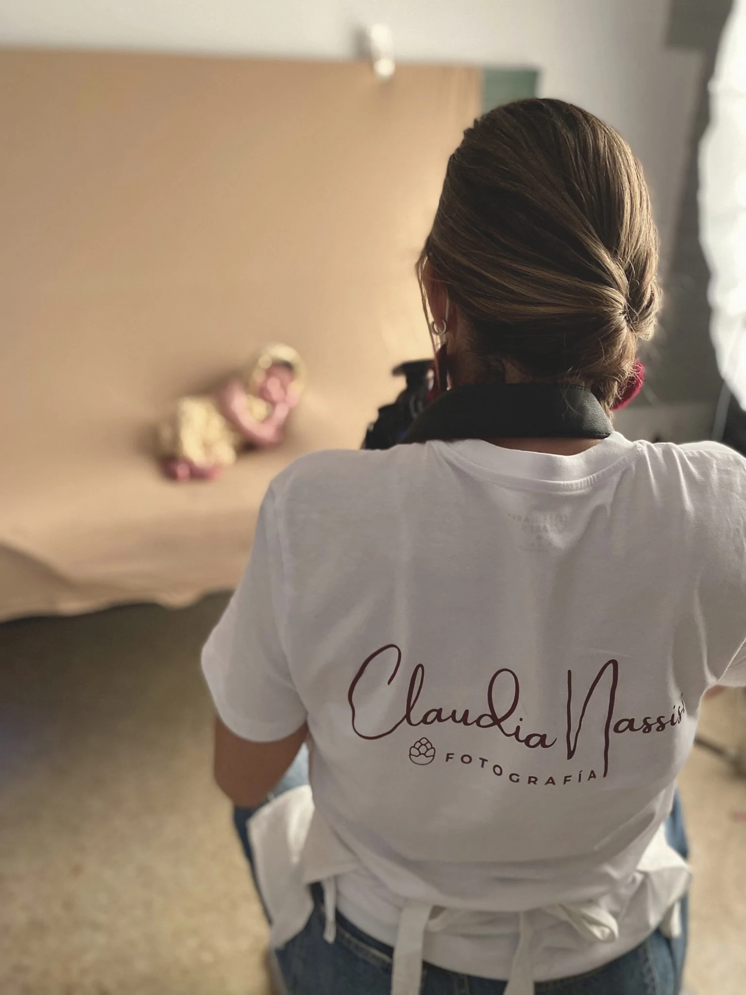 Claudia Nassisi de espaldas, fotografiando a un recién nacido en su estudio